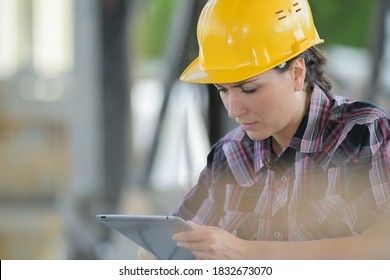 Woman wearing hardhat looking at tablet