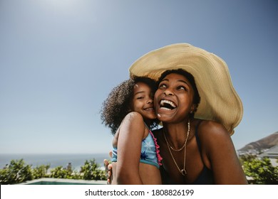 Woman wearing hat enjoying summer vacation with her daughter. African woman with her daughter having fun at the poolside. - Powered by Shutterstock