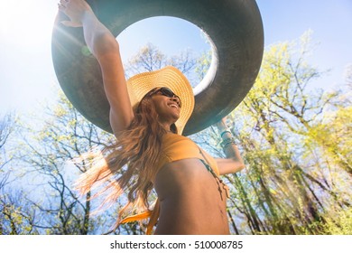 Woman Wearing Hat And Sunglasses Carrying Inner Tube Above Head