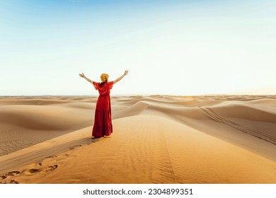 Woman wearing hijab walking in the desert sand dunes at sunset - Happy traveler with arms up enjoying freedom outside - Wanderlust, wellbeing, happiness and travel concept - Powered by Shutterstock