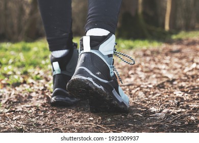 Woman wearing hiking boots on a forest trail close up at ground level from behind 