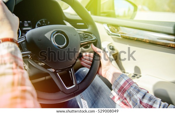Woman wearing holiday vintage shirt changing cruise\
control settings while driving on UK highway - driving left hand\
drive