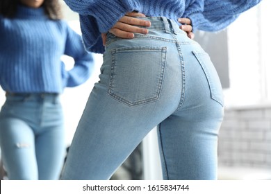 Woman wearing jeans near mirror indoors, closeup