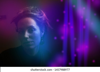 Woman wearing jewelry in colorful bright lights, posing in studio