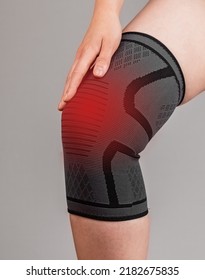Woman wearing knee brace to reduce pain or prevent injury during sport. Female leg with red point. Sprained, ruptured ligaments, meniscus tear, tendinitis, arthritis. High quality photo