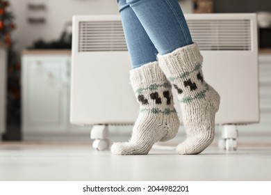 Woman wearing knitted socks at home. Concept of heating season