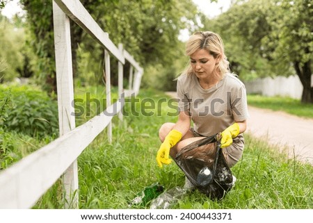 woman wearing latex gloves picking up litter to garbage bag, holding used plastic bottle in hand, takes care of planet