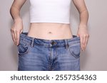 Woman wearing loose pants demonstrating successful weight loss. Fitness, dieting and wellness concept.