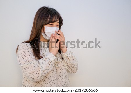 A woman wearing a mask and coughing painfully