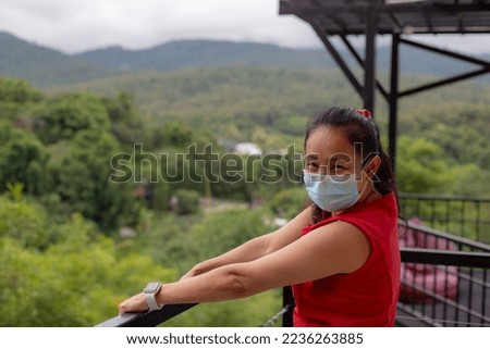 Woman wearing a mask holding a steel railing