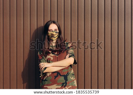Woman Wearing Matching Camouflage Mask and Shirt. Modern stylish model keeping fashionable and hopeful 
