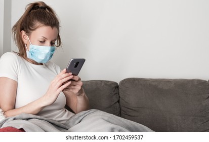 Woman wearing medical face mask holding phone while sitting on couch. Covid-19 outbreak pandemic. Stay home concep. - Powered by Shutterstock