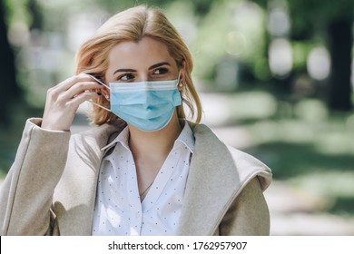 Woman wearing medical face mask. Uncomfortable mask. Touching face to adjust the mask. - Powered by Shutterstock