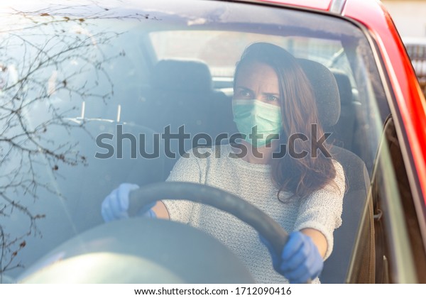 Woman wearing medical face\
protection mask and protective gloves, driving a car; covid-19\
protection and prevention measures and safety protocols for\
everyday life