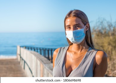 Woman wearing medical mask at beach. Life after pandemic, obligatory use of face mask in public spaces, copy space - Powered by Shutterstock