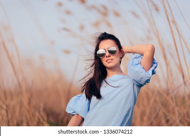 Woman Wearing Mirror Sunglasses in Outdoor Fashion Portrait. Female model wearing cool silver shades and of shoulder top
