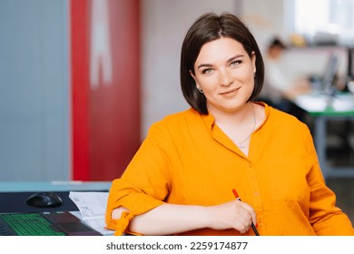 a woman wearing a orange blouse with laptop in a office. the concept of a business female portrait. office rent for an hour. - Shutterstock ID 2259174877