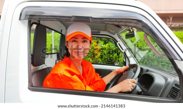 Woman wearing
orange work clothes and a light
car