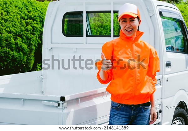 Woman wearing
orange work clothes and a light
car