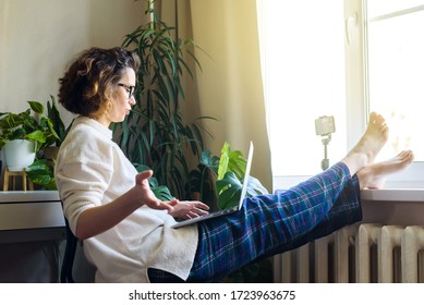 a woman wearing pajamas in her house communicates video conference at work on laptop - Shutterstock ID 1723963675