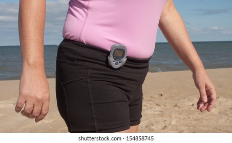 Woman Wearing A Pedometer Walking On The Beach