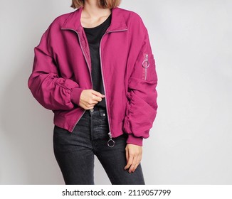 Woman wearing pink bomber jacket and black jeans isolated on white background. Copy space