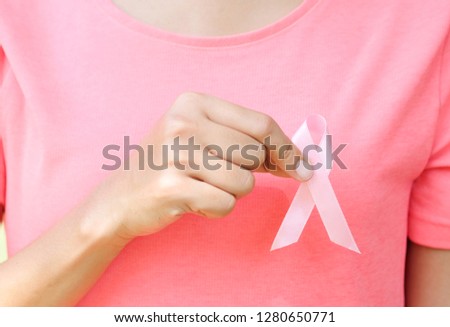 woman wearing pink shirt, her hand holding a pink ribbon. Breast Cancer Symptoms Health and protection concepts