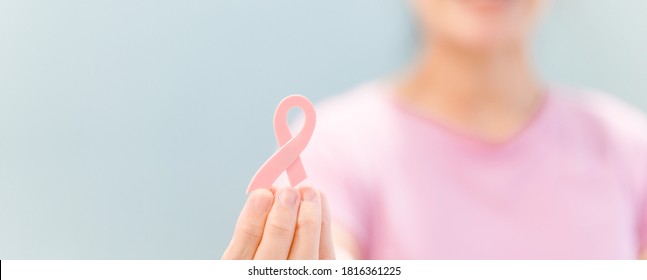 Woman wearing pink t shirt holding pink ribbon.Oncology.breast cancer awareness, October pink, World cancer day concept.banner background.Healthcare Tele medicine.Fight and Survivor with hope.