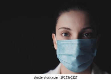 Woman wearing protective face mask for safety during COVID-19 with black background - Shutterstock ID 1913360227