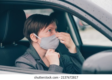 Woman Wearing Protective Face Mask In Car During Covid-19 Pandemics, Looking At The Mirror, Selective Focus