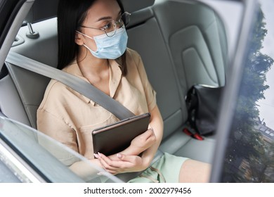 Woman Wearing Protective Mask Is Holding Her Tablet In A Car