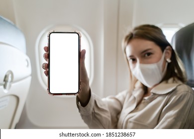 Woman Wearing Protective Masks On Board Of An Airplane With White Screen Mobile Mockup In Hand. 