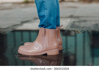 Woman Wearing Rain Rubber Boots Walking Running And Jumping Into Puddle With Water Splash And Drops In Autumn Rain.