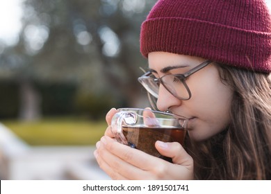 Woman Wearing Red Beanie And Glasses Drinking Tea Outdoor

