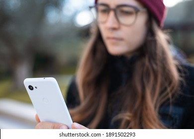 Woman Wearing Red Beanie And Glasses Using A Mobile Phone Outdoor