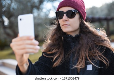 Woman Wearing Red Beanie And Sunglasses Taking A Selfie Outdoor