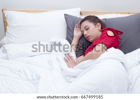 Woman wearing red dress sleeping in bed.