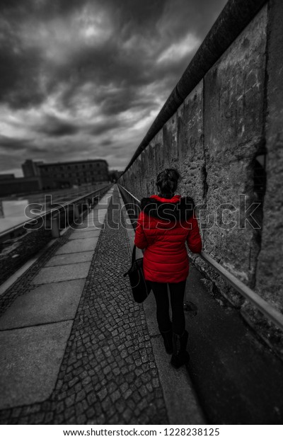 Woman wearing red jacket visits remains of Berlin\
Wall Germany