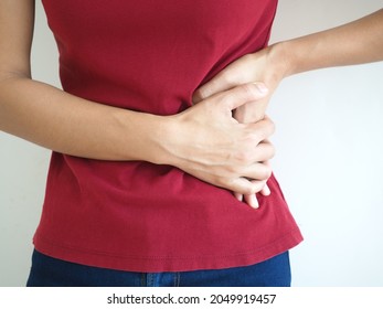 Woman wearing red t shirt on a white background hold hands on his stomach, liver pain, pancreas, kidneys problems. closeup photo, blurred. - Shutterstock ID 2049919457