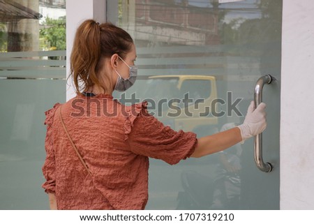 Woman wearing rubber protective gloves and medical mask while opening door. Virus and illness protection. Hands disinfection as prevention of Coronavirus disease.	