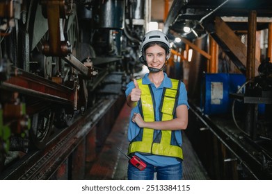 woman wearing a safety vest and helmet is giving a thumbs up. She is standing in a train station - Powered by Shutterstock