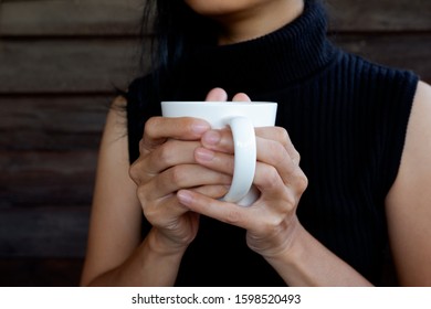 Woman Wearing A Sleeveless Sweater Holding A White Glass