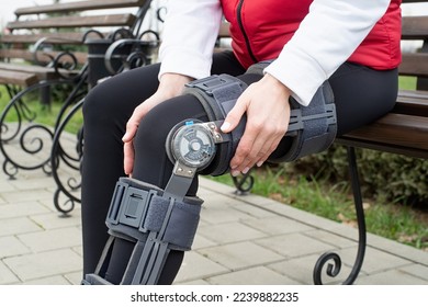 Woman wearing sport clothes and knee brace or orthosis after leg surgery, walking in the park. Medical and healthcare concept. - Powered by Shutterstock