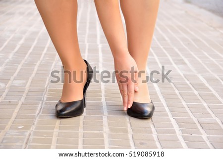 woman wearing stilettos and touching her foot bunion. Hallux valgus by use of narrow shoes