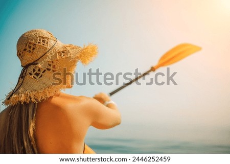A woman wearing a straw hat is paddling a canoe on a sunny day. Scene is relaxed and carefree, as the woman enjoys her time on the water.