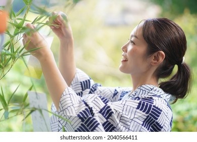 A woman wearing a strip of paper on Tanabata bamboo 