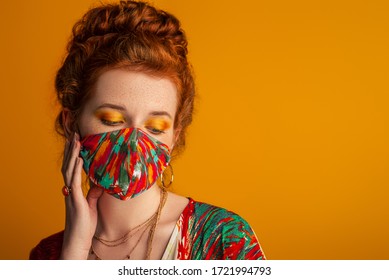 Woman Wearing Stylish Outfit With Designer Protective Bold Colors Face Mask, Matching Eyes Makeup, Dress. Trendy Fashion Accessory During Quarantine Of Coronavirus Pandemic. Copy, Empty Space For Text