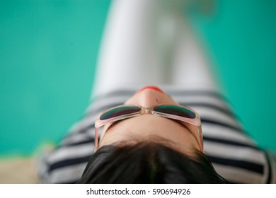 Woman Wearing Sunglasses Lying Sprawled Out On Her Back, View From The Top Of The Head