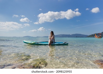 Woman wearing sunglasses sitting on the paddleboard on a water