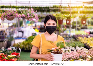 Woman Wearing Surgical Face Mask And Buying Plants At Garden Center